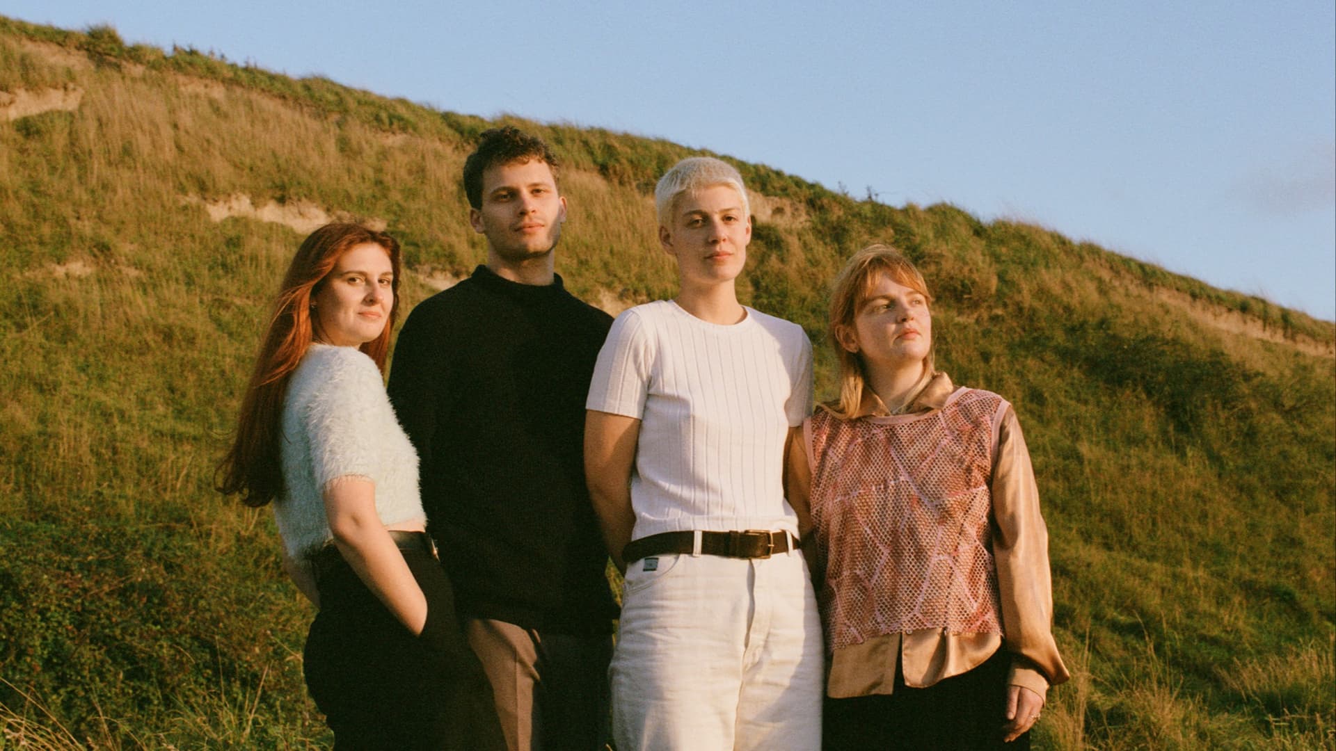 The four members of porridge radio standing in a field.